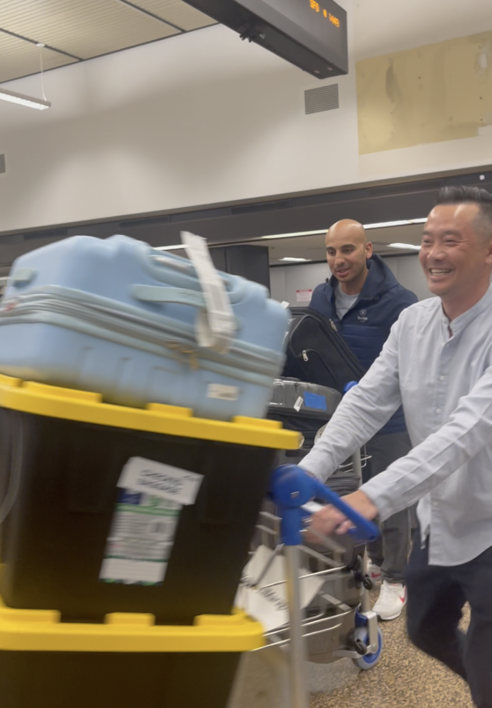 A personal relocation assistant helps his client wheel luggage from baggage claim to his private transportation at the airport